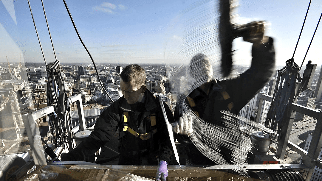 Two commercial window cleaners on hydraulic platform cleaning windows.