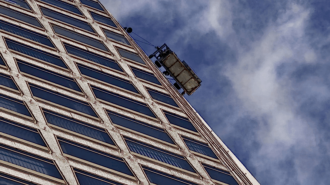 Commercial window cleaning cradle on the side of a high-rise building.